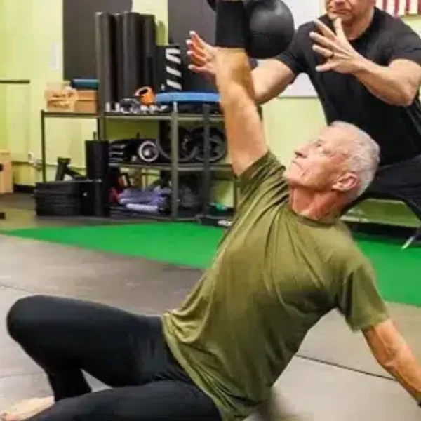A coach guiding an older adult through a strength exercise in Tucson