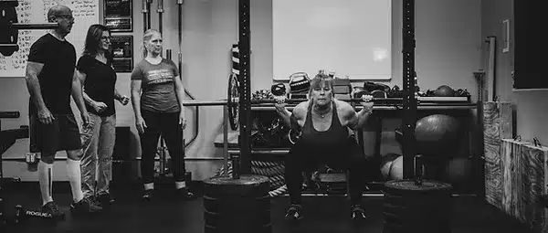 An athlete squatting with a barbell during a powerlifting class in Tucson